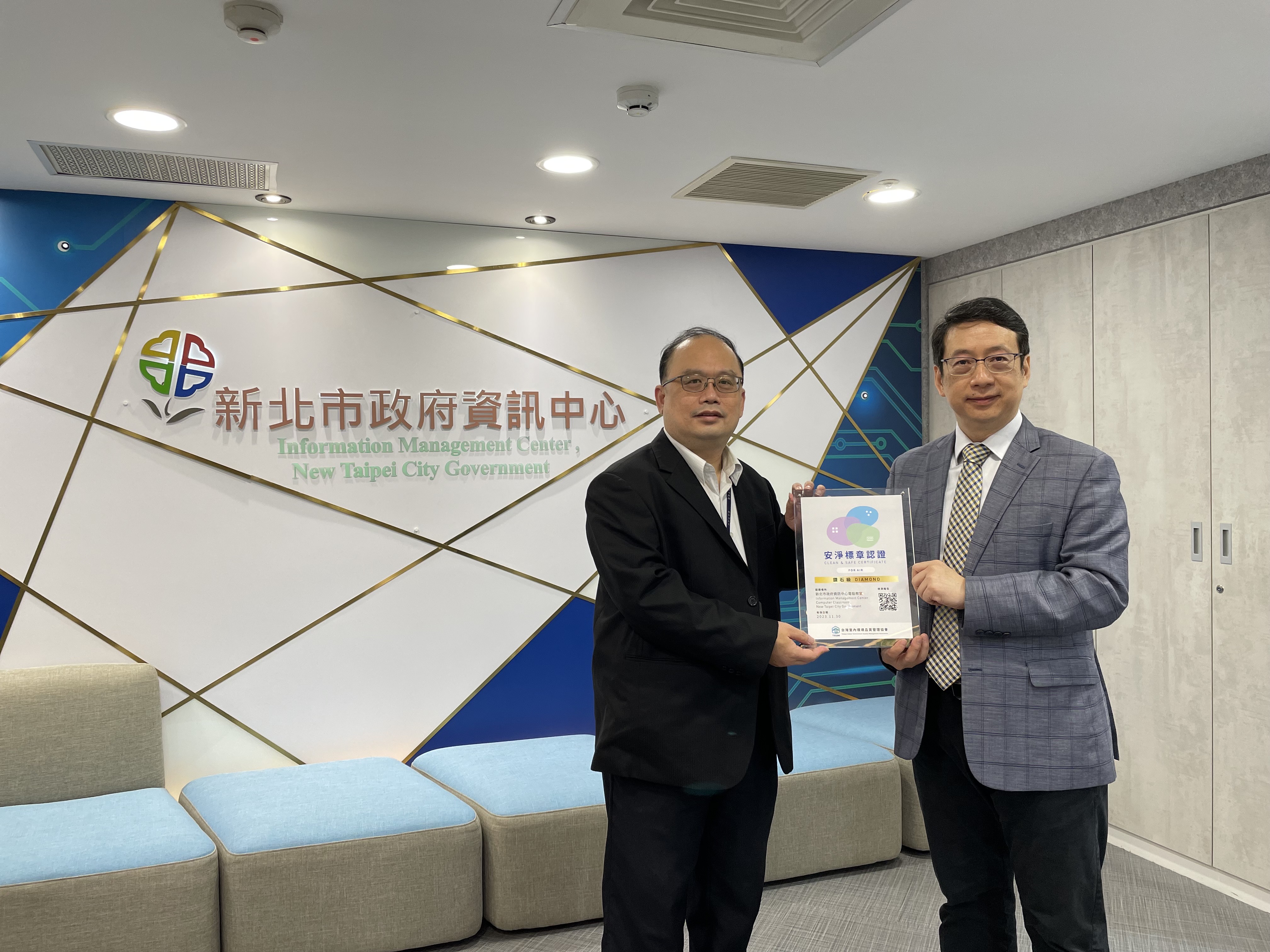 圖一、全台首座電腦教室安淨標章認證，由新北市資訊中心主任陳富添代表接受台灣室內環境品質管理協會理事長鄭仁雄頒發認證標章。